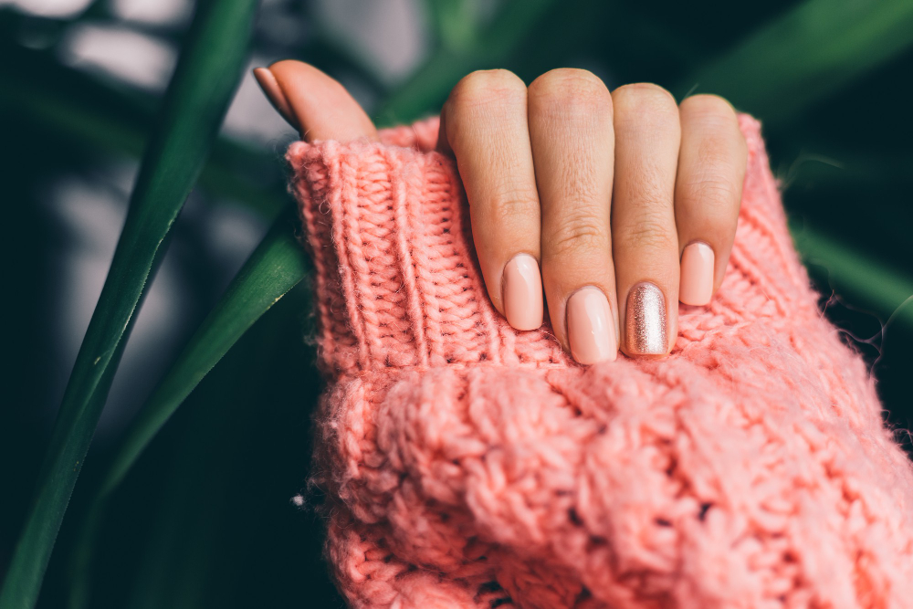 pretty-nude-color-manicure-one-finger-shiny-golden-knitted-pink-wool-pillover-background.jpg